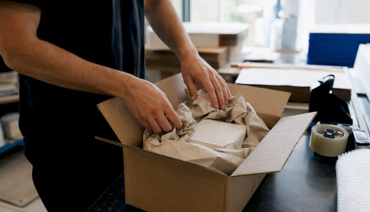 Hands packing fragile item in corrugated box