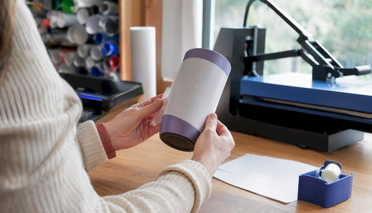 Hands sliding sublimation shrink sleeve on tumbler